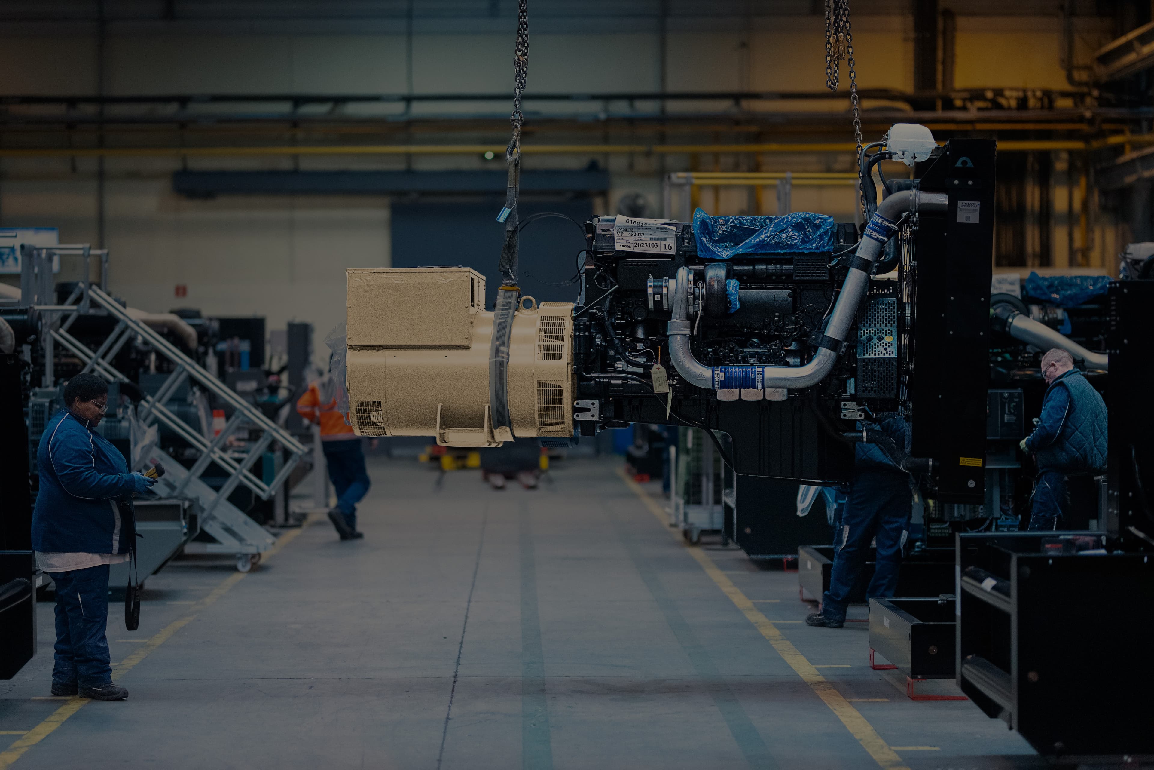 A production operator is handling a generator sets using an overhead crane