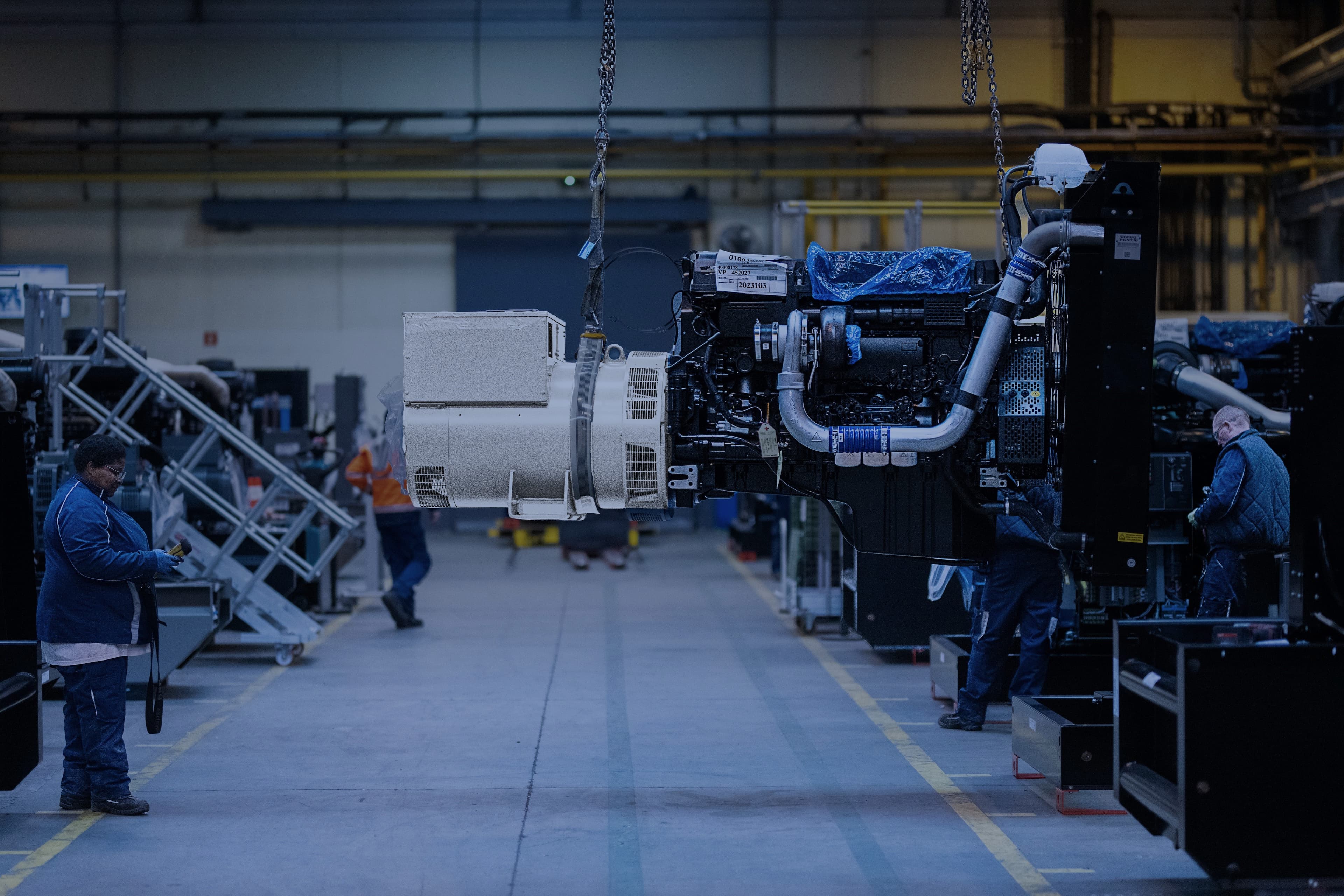 A production operator is handling a generator sets using an overhead crane